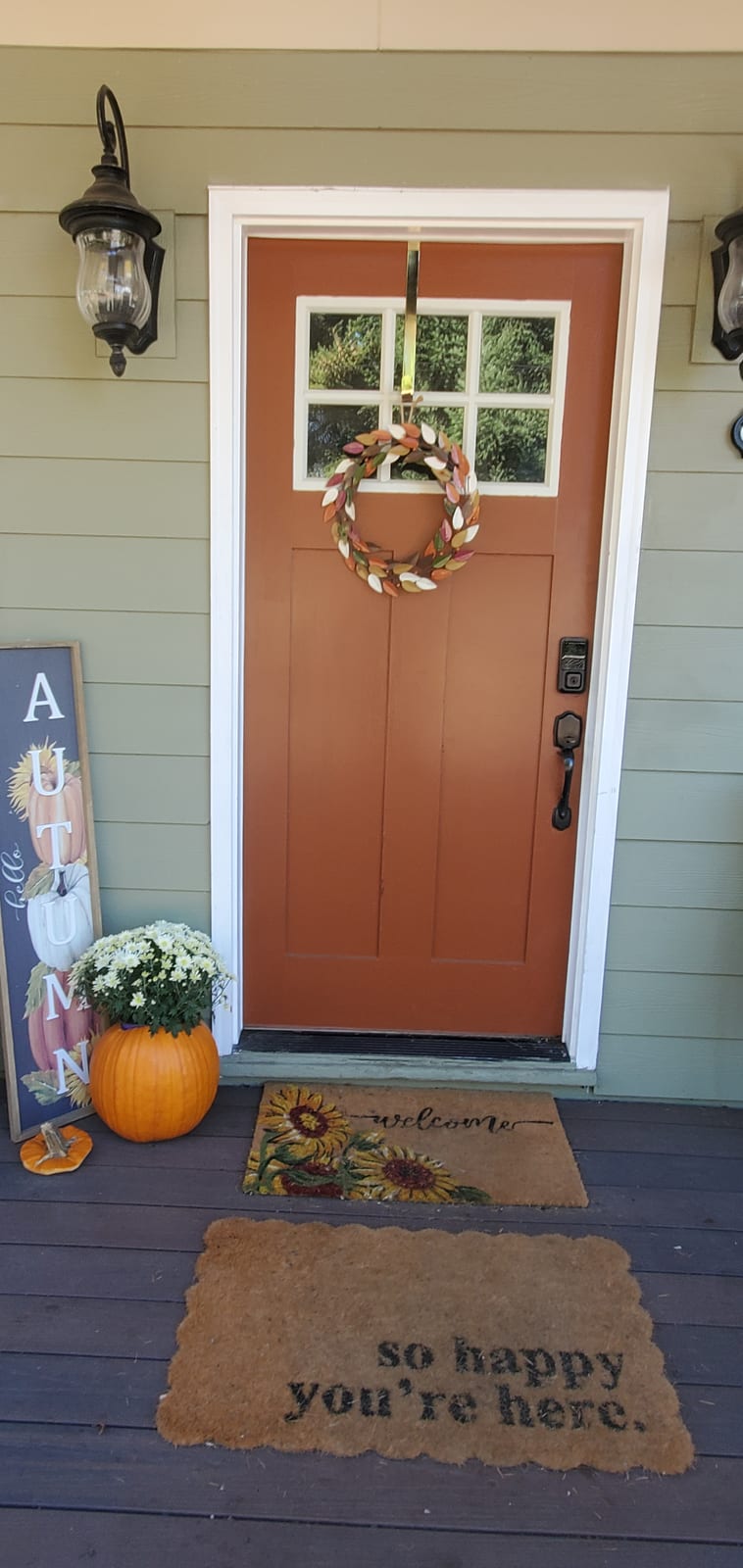 Front door with an autumn wreath and welcome mat