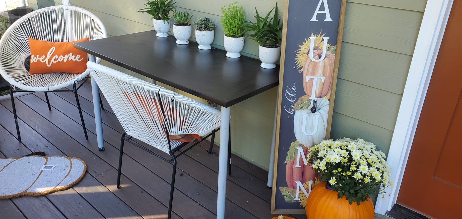 Porch table with potted plants and an autumn sign