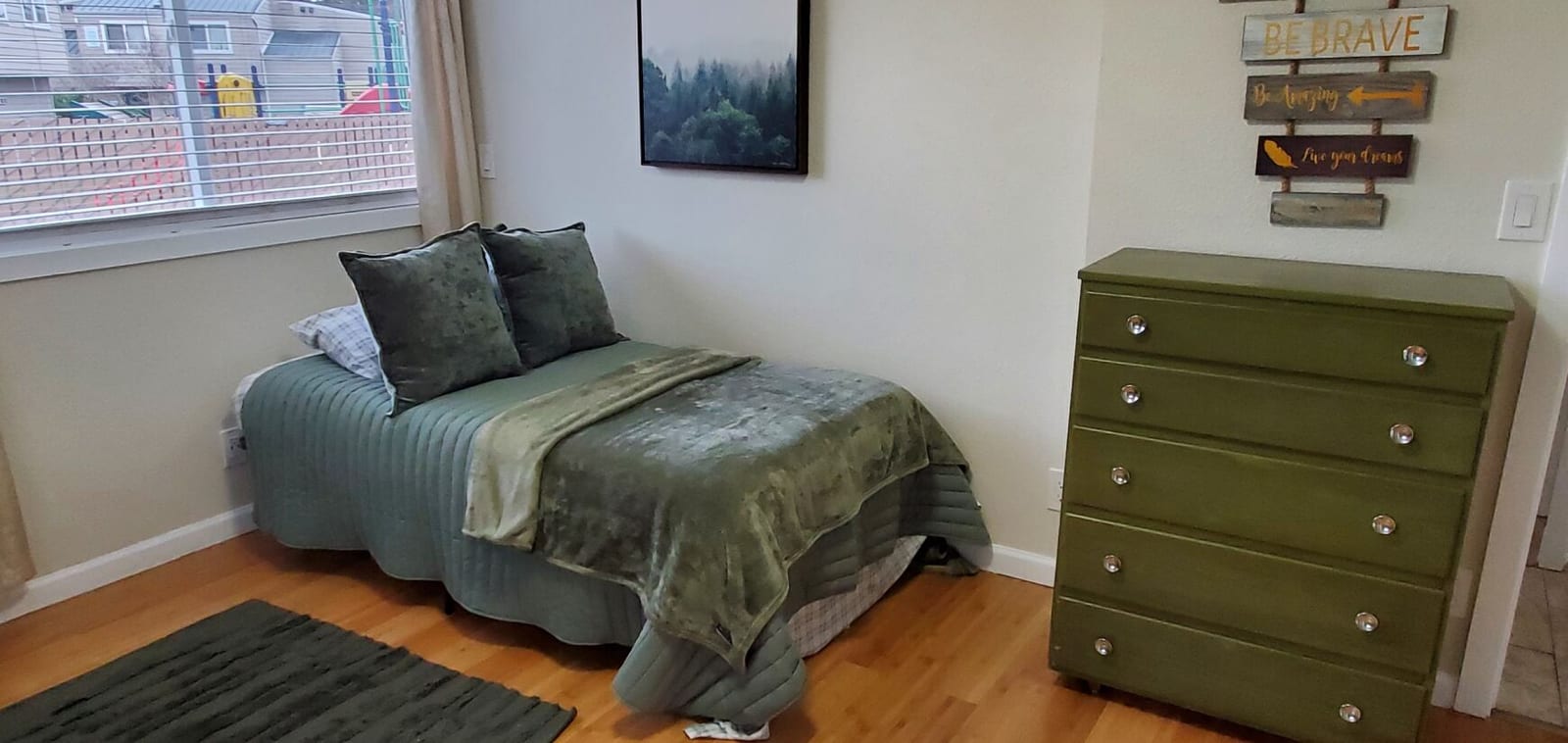 Bedroom with green bedding and a “Be Brave” sign